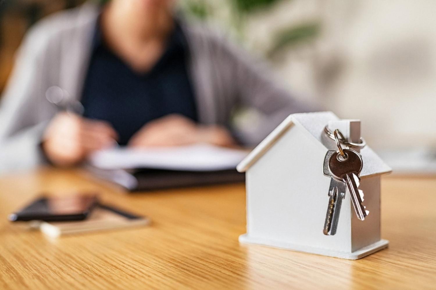 Keys to a Dubai apartment next to a signed home insurance policy on a desk